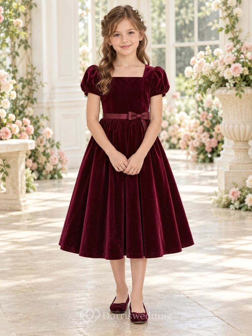 Vestido de niña de flores de terciopelo burdeos, corte en A, largo hasta la rodilla, escote cuadrado, mangas abullonadas, con fajín de satén y lazo.